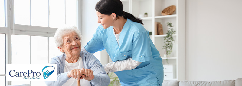 Elderly Woman holding cane in her home with her nurse by her.