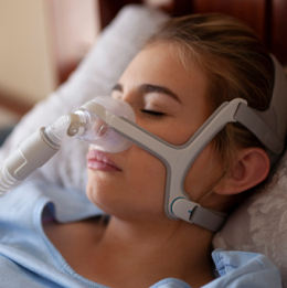 Woman sleeping with CPAP mask on and machine connected