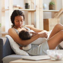 Woman nursing baby while lying on the couch