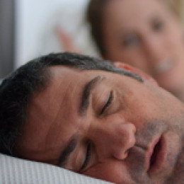 Man snoring with partner behind him looking annoyed