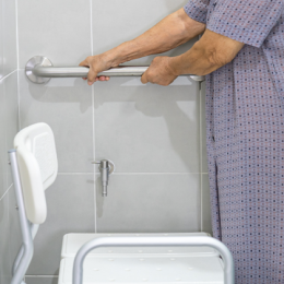 Elderly woman holding onto grab bar in the bathroom.