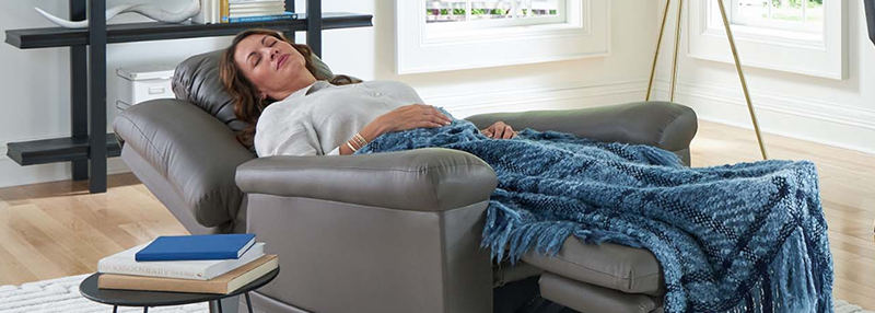 Woman napping reclined in grey leather lift chair in her home