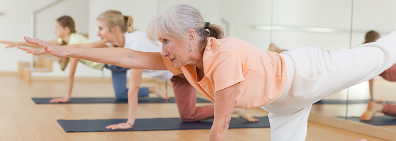 Older woman doing yoga in a fitness classroom