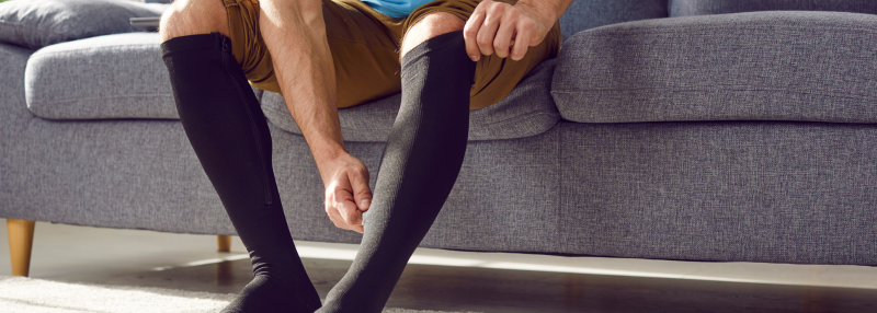 Man pulling up compression stocking